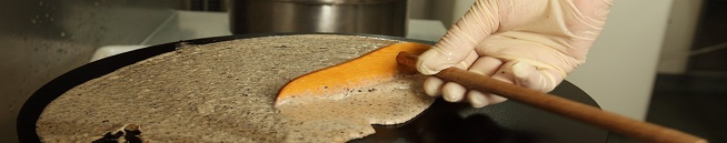 Crêpier étalant sa pâte à crêpe sur une billig Crêpier étalant sa pâte à crêpe sur une billig